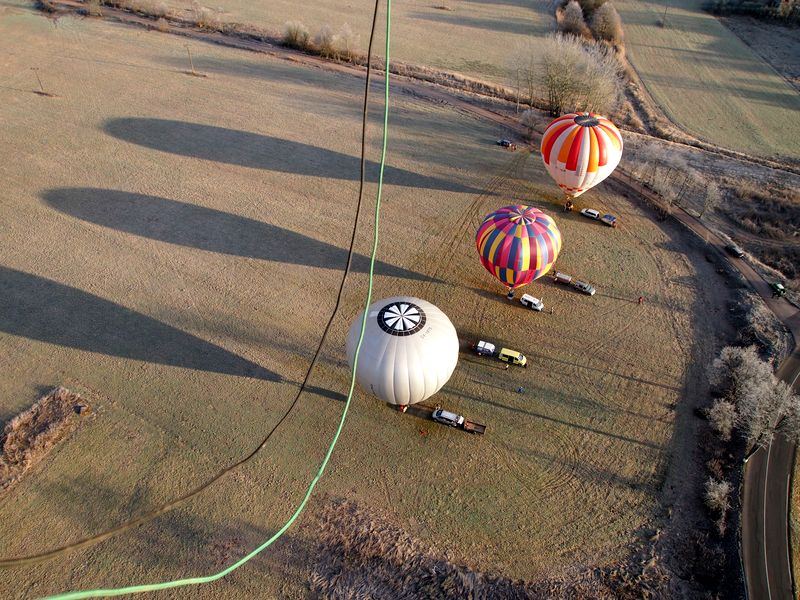 Tři balóny na poli u aut připravené na vzlet