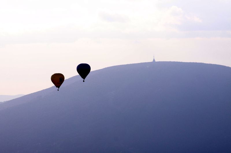 Dva letící balóny v mlze s výhledem na okolní hory