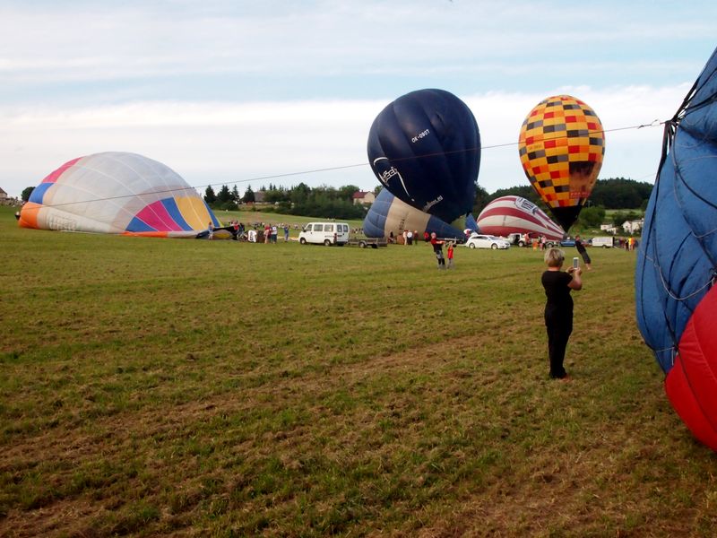 Pole plné nafukujících se horkovzdušných balónů